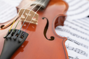 Close-up view of a wooden violin resting on sheet music, showcasing intricate details of the...