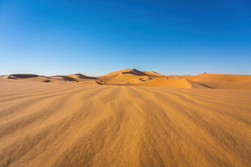 Expansive desert landscape with sand dunes and clear blue sky