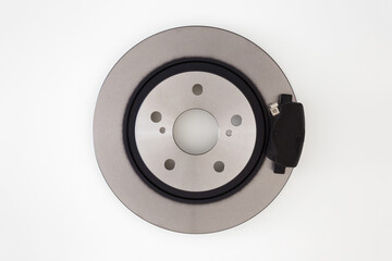 New brake disc with dark black pad isolated on light gray table background. Car spare parts. Closeup. Top down view.