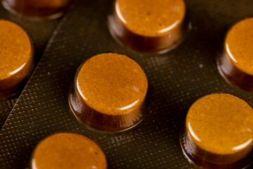 cylindrical orange tablets packed in a blister , whole orange tablets packed in a metal-plastic blister