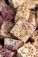 diced ripe red pitaya with lots of small black seeds and white soft sweet flesh inside, sweet ripe dragon fruit with black seeds and light flesh cut in half into small cubes