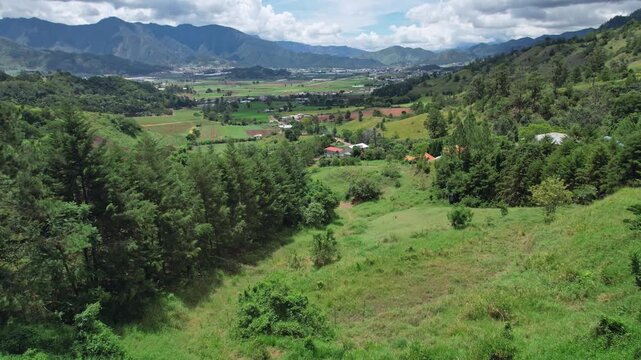 Lush green Constanza valley, village, mountains, and pine forests, agricultural landscape in Dominican Republic, central highlands. Aerial forward