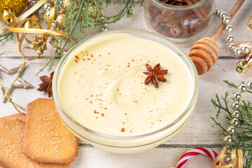 Christmas breakfast Eggnog Greek Yogurt. Bowl of yogurt, whipped with egg yolk, nutmeg, vanilla and spices, on Christmas decorated background. Tasty, rich in protein healthy eggnog version