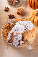 Pumpkin Pie Greek Yogurt Breakfast Bowl with pumpkin puree and seeds, pecan nits, graham crackers, topped with whipped cream and cinnamon, tasty autumn season snack or breakfast recipe