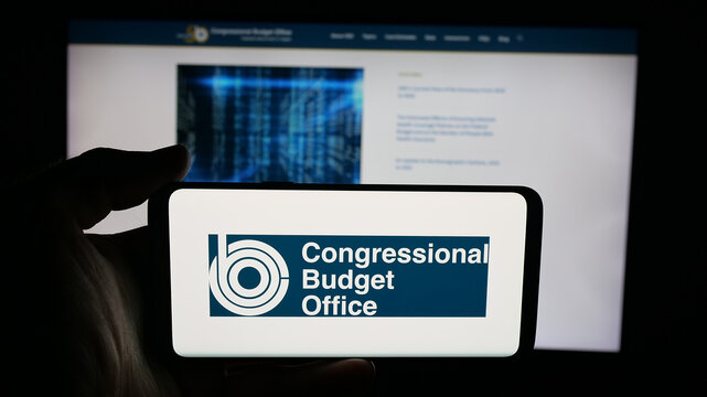 Stuttgart, Germany - 09-26-2025: Person holding cellphone with logo of US agency Congressional Budget Office (CBO) on screen in front of webpage. Focus on phone display.