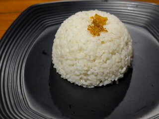 White rice with fried onions on a black plate.
