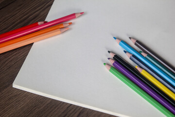 Obraz premium Group of colorful pencils diagonally aligned on a blank white sheet, ready for design or drawing with ample copy space.
