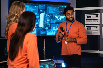 Startup leader giving a presentation on mobile app development with futuristic digital interface on screen, UX UI designer team meeting, teamwork, brainstorming, and digital transformation in business