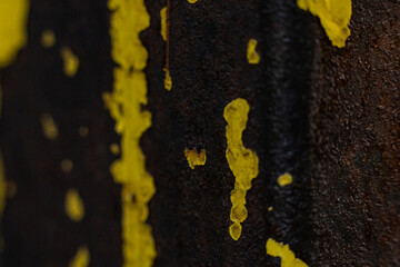Rusty metal texture with vibrant yellow paint splatters revealing decay and age in an industrial setting