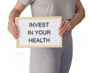 woman dressed in sportswear with a message on a whiteboard. invest in your health