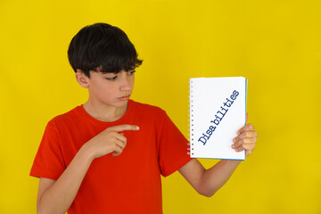 childhood and disabilities. Preteen boy pointing to a notebook with the word written on it.