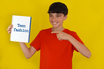 adolescence and fashion concepts. smiling preteen boy pointing to a notebook