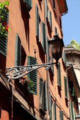 Fachada de casas con persianas venecianas y farol antiguo.