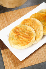 Pan-fried pork dumplings potstickers on white plate with bamboo steamer traditional Asian food