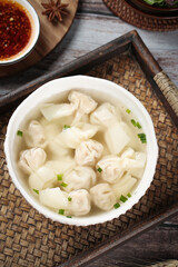 Handmade Wontons in Clear Broth Soup with Green Onions and Spicy Dipping Sauce on Bamboo Tray