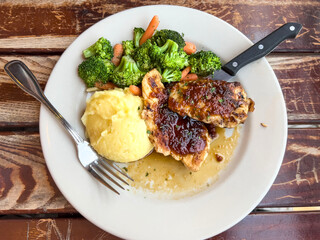 Grilled Chicken with Barbecue Sauce, Mashed Potatoes, and Steamed Vegetables on Rustic Wooden Table