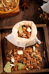 Aromatic spice collection in cloth bag with herbs and seasonings on rustic wooden background