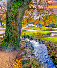 Small decorative water cascade in public city park at autumn season