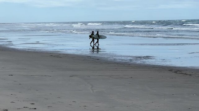 Zwei Surfer mit einem Surfbrett am Strand von Ofir in Portugal