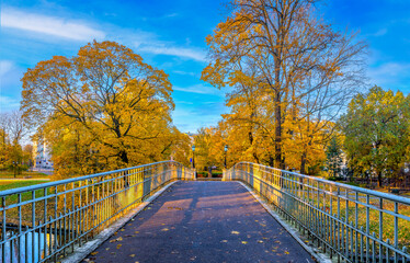 Pedestrian bridge in old public city park, golden autumn season