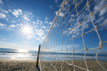 A beach volleyball net stands on sandy shores under a bright sun, with blue sky and ocean waves in the background