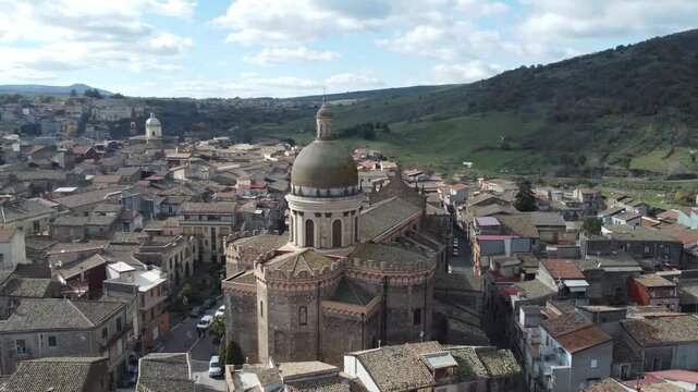 Aerial drone footage of Randazzo in Sicily focusing on the historic center with Basilica di Santa Maria Assunta and the town&rsquo;s medieval architecture, with Mount Etna rising clearly in the background.