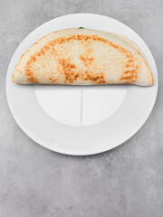 Piadina romagnola with spinach and cheese filling on white plate
