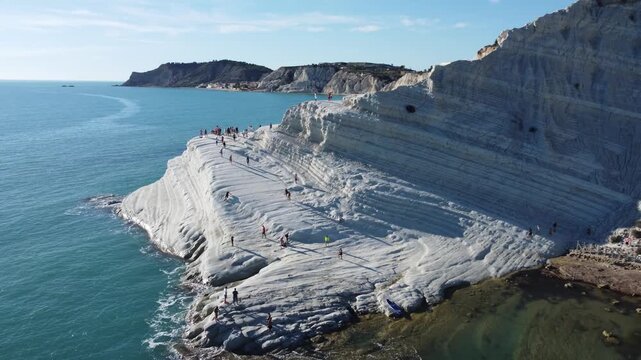 Cinematic 4K drone footage of Scala dei Turchi in Sicily, focusing on the iconic white limestone cliffs, turquoise Mediterranean waters, and the dramatic coastal scenery under bright summer skies.