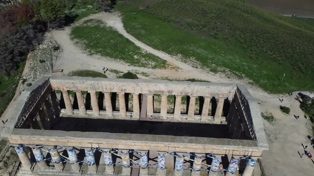 Stunning 4K footage of the Doric Temple of Segesta in Sicily, capturing the ancient Greek architecture surrounded by rolling hills, Mediterranean scenery, and bright summer sunlight in the Parco Arche