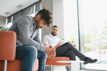 Fototapeta premium Upset arab man receiving psychological support from counselor in modern office