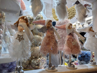 Christmas angel dolls and festive decorations displayed in a shop window, featuring winter holidays and magic concept