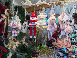 Hanging handmade Christmas dolls and festive winter decorations displayed for sale in a vibrant holiday market