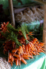Vibrant orange baby carrot bunch displayed an outdoor market stall, offering fresh organic produce....