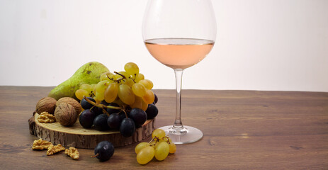 Tagliere con noci e uva, calice di vino rosè, banner