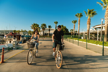 Young Couple Cycling to Yacht at Marina