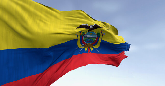 Waving Ecuador flag with coat of arms against a clear blue sky