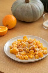 Autumn pumpkin dish. Orange honey pumpkin with sesame seeds on a wooden table.