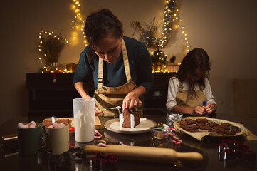 Mother And Daughter Baking Gingerbread House Together By Cozy Christmas Lights
