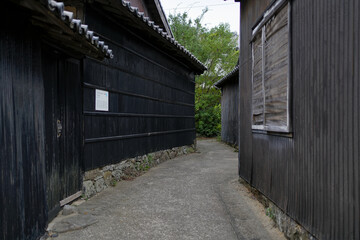 Fototapeta premium A quiet narrow alley between traditional black wooden houses in a historic Japanese village, showing the atmosphere of old architecture.