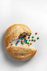 A round loaf of bread broken in half, vitamins are poured out of it.
