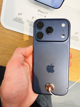 Blue iPhone 17 held in hand displaying triple camera setup and sleek back design