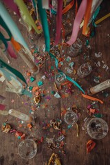 Fototapeta premium Overhead view of messy wooden party table with empty champagne glasses and confetti aftermath