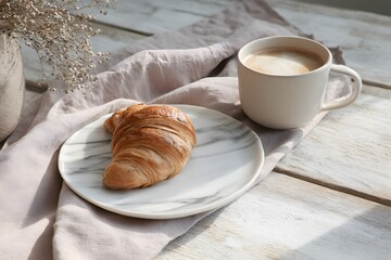 Serene morning still life with croissant, coffee, and sunlight on wood