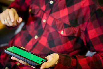Man in red plaid shirt browsing phone horizontally
