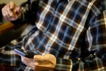 Man in plaid shirt using smartphone indoors casually