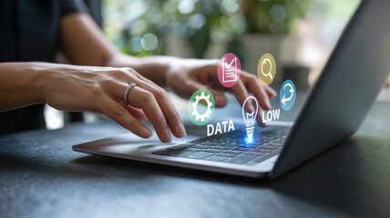 Close up of a womans hands typing on a laptop with data and technology icons floating above the keyboard