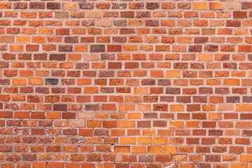 A textured wall made of red and brown bricks. The bricks vary in size and color, creating a rustic appearance. Ideal for backgrounds or architectural designs.