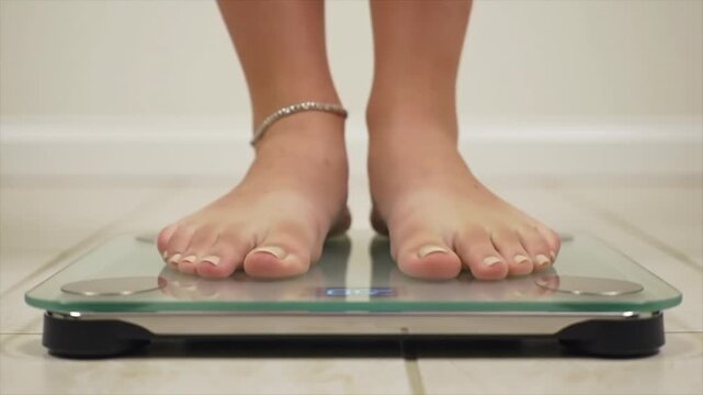 Person stepping on a bathroom scale to check their weight. Diet progress