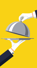 Fototapeta premium A person in a white glove lifts the lid off a silver cloche revealing a delicious meal on a platter.