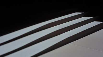 Light and Shadow, Streetlight shadows cast intricate patterns on concrete, creating a striking urban scene at dusk.
